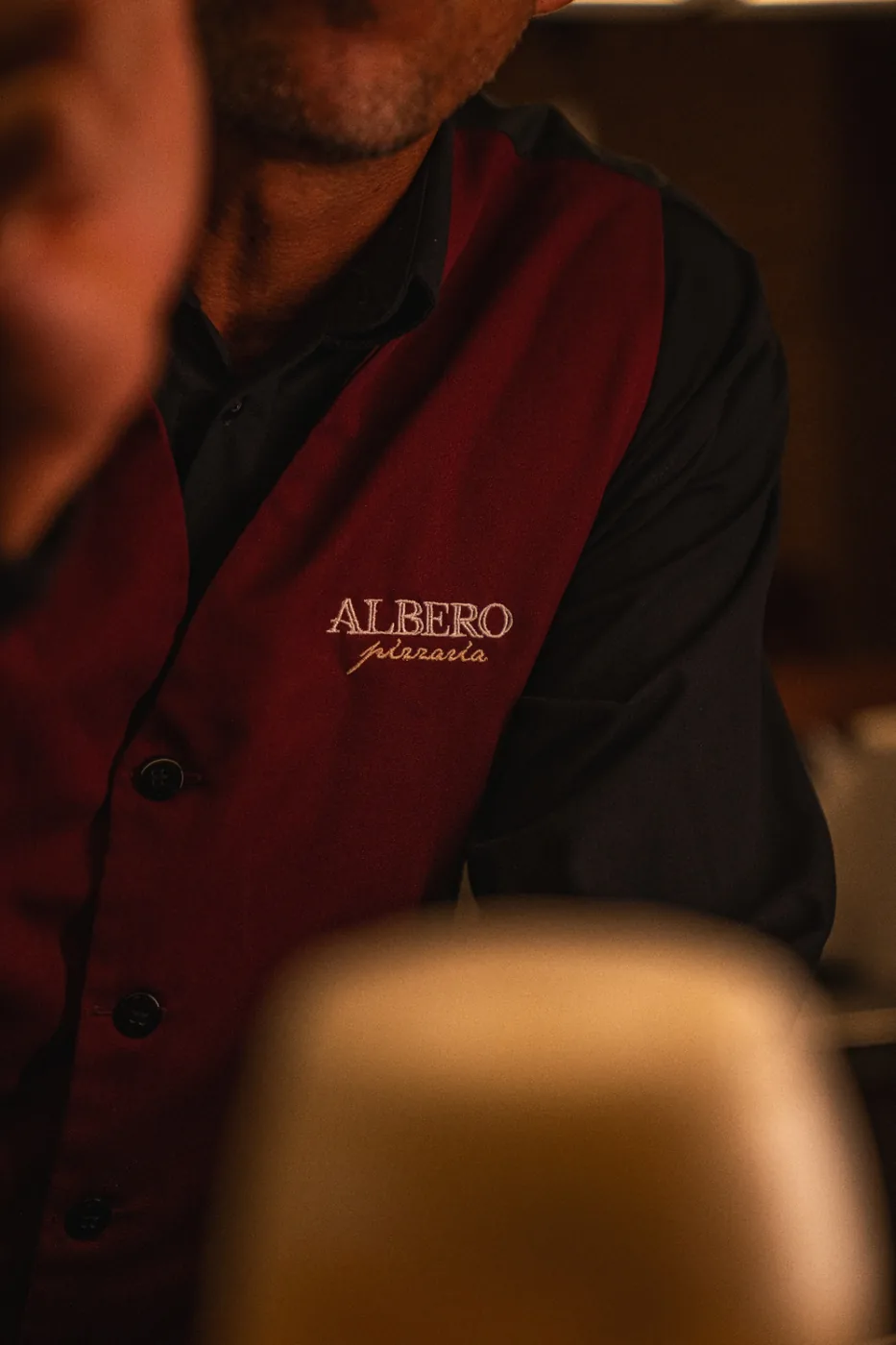 Colete vinho da equipe da Albero, com bordado prata do logotipo.